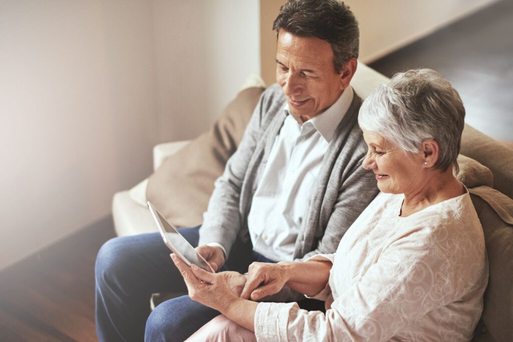 tech-education-for-seniors.jpg - Anthem Lakes Senior Living Senior man and woman seated on couch looking at an iPad