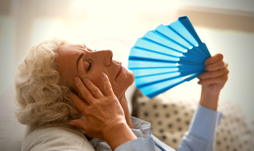 blog-post-overheating-in-senior-citizens.jpg - Anthem Lakes Senior Living Senior woman with handheld fan